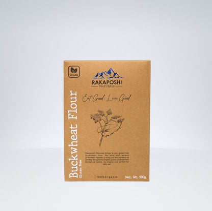 A package of Rakaposhi Naturals Buckwheat Flour, displaying the brand name, product type, and a small illustration of buckwheat flowers. The package is brown with a white mountain range logo and text.